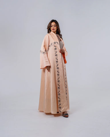 عباية فاخرة إصدار محدود، صُممت من قماش تهاني بوتيك الحصري الممزوج باللينن والحرير الطبيعي الخالص، وتزينها تطريزات يدوية محبوكة بخيوط الريسم بتفاصيل نباتية أنيقة تمنحها لمسة فنية راقية وحضورًا يفيض بالفخامة